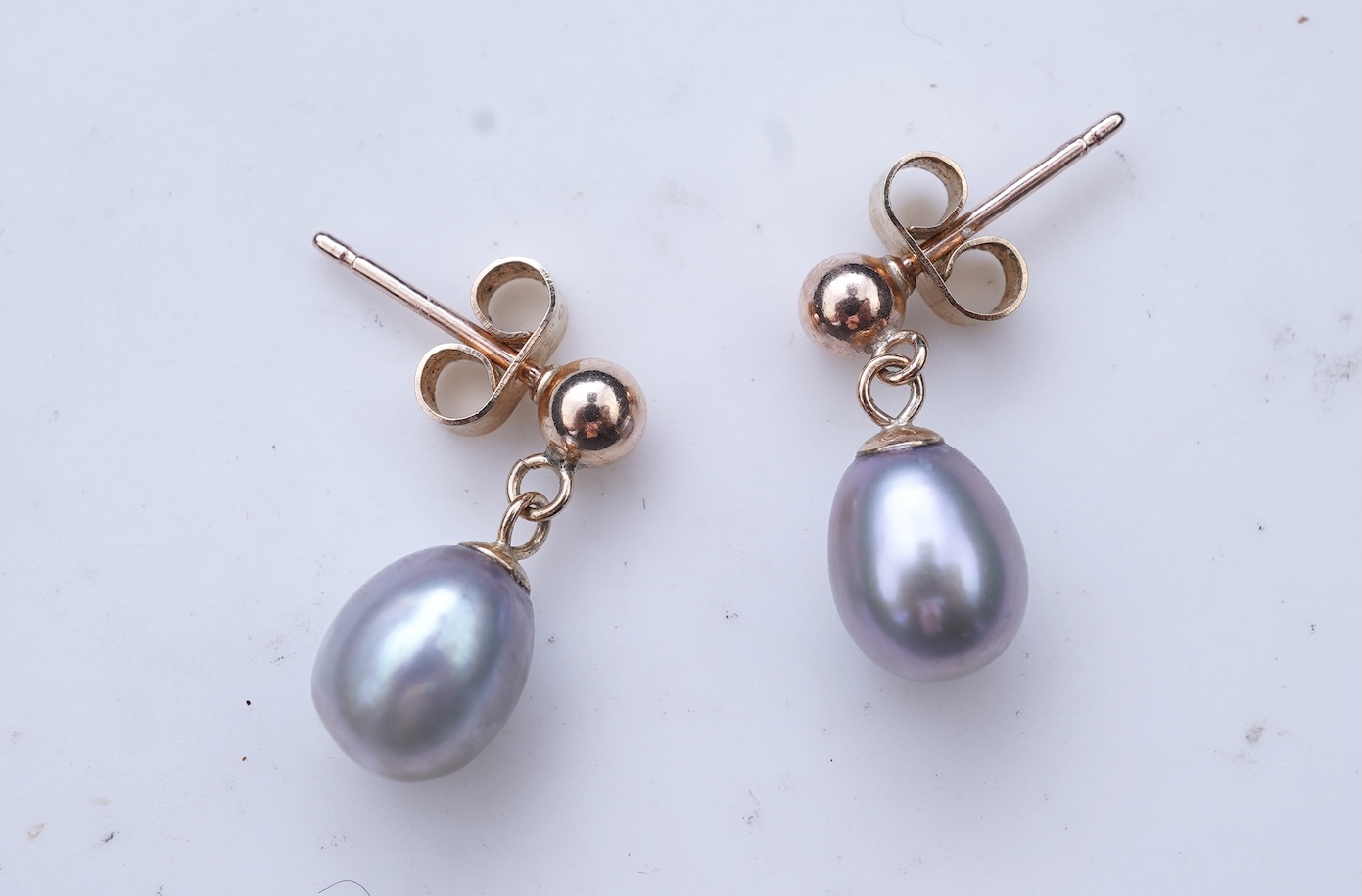 A group of cultured pearl jewels, comprising: two pairs of cultured pearl drop earrings, longest 3cm, mounted in gold; and two cultured pearl brooches mounted in 9ct gold, longest 4.1cm, British hallmarks, combined gross